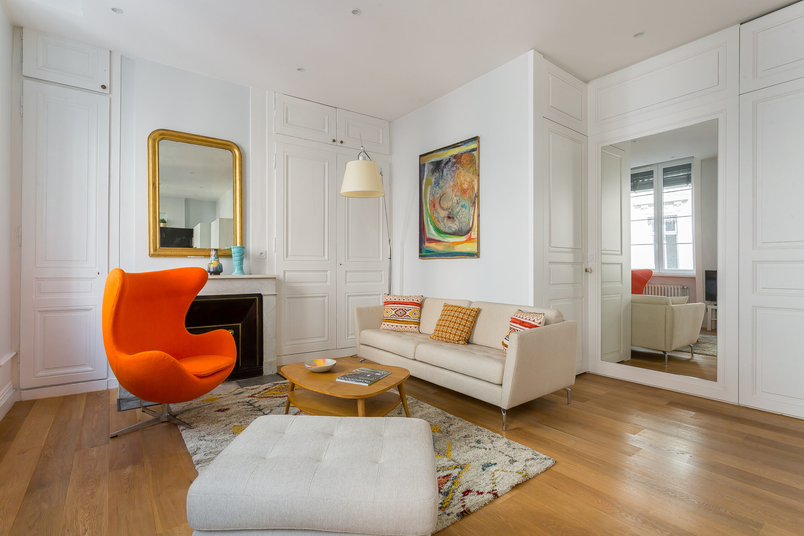 Charité — Salon avec canapé clair, fauteuil orange et cheminée