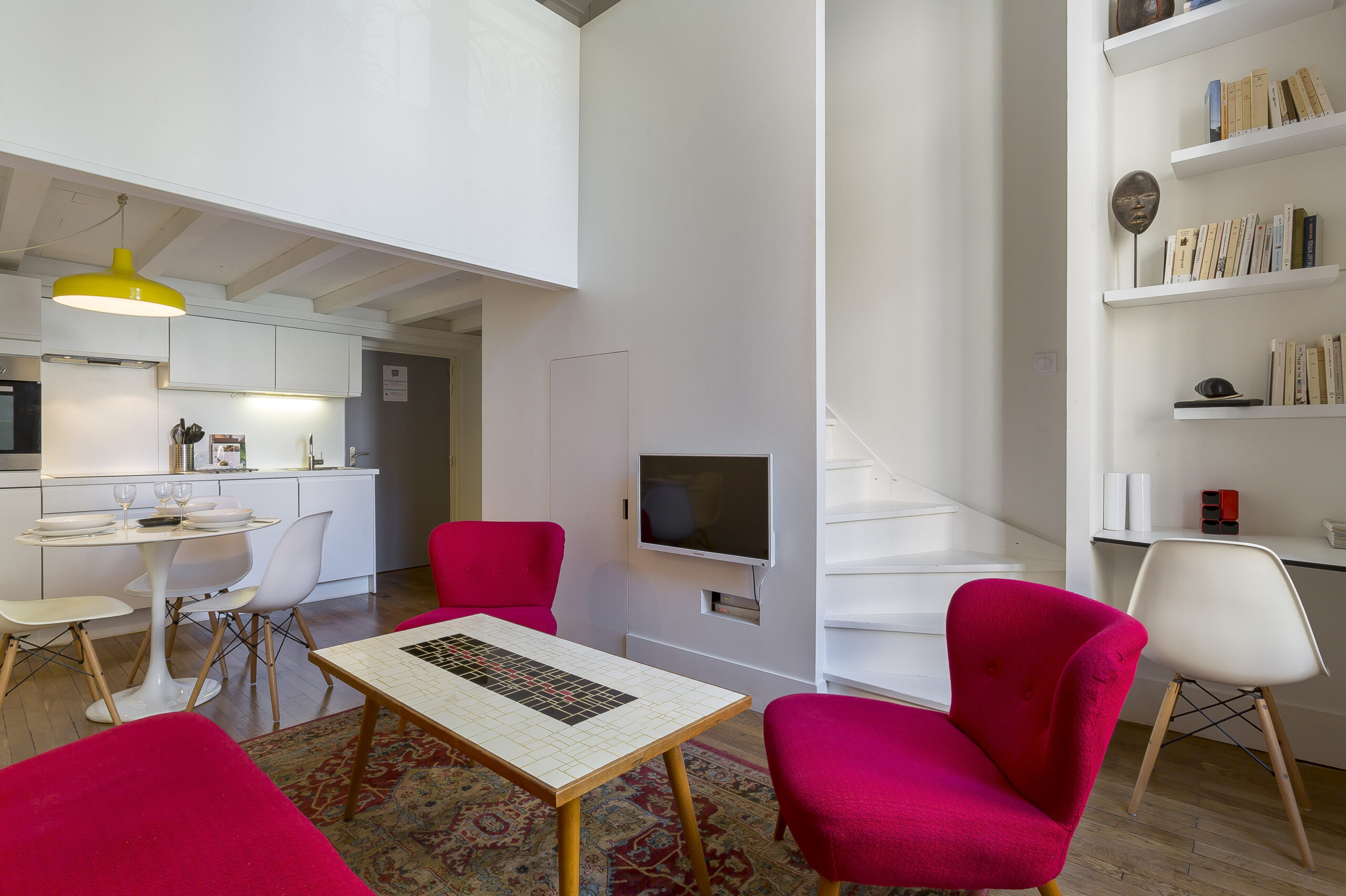 Opéra Mineur — Séjour avec fauteuil rose et cuisine ouverte