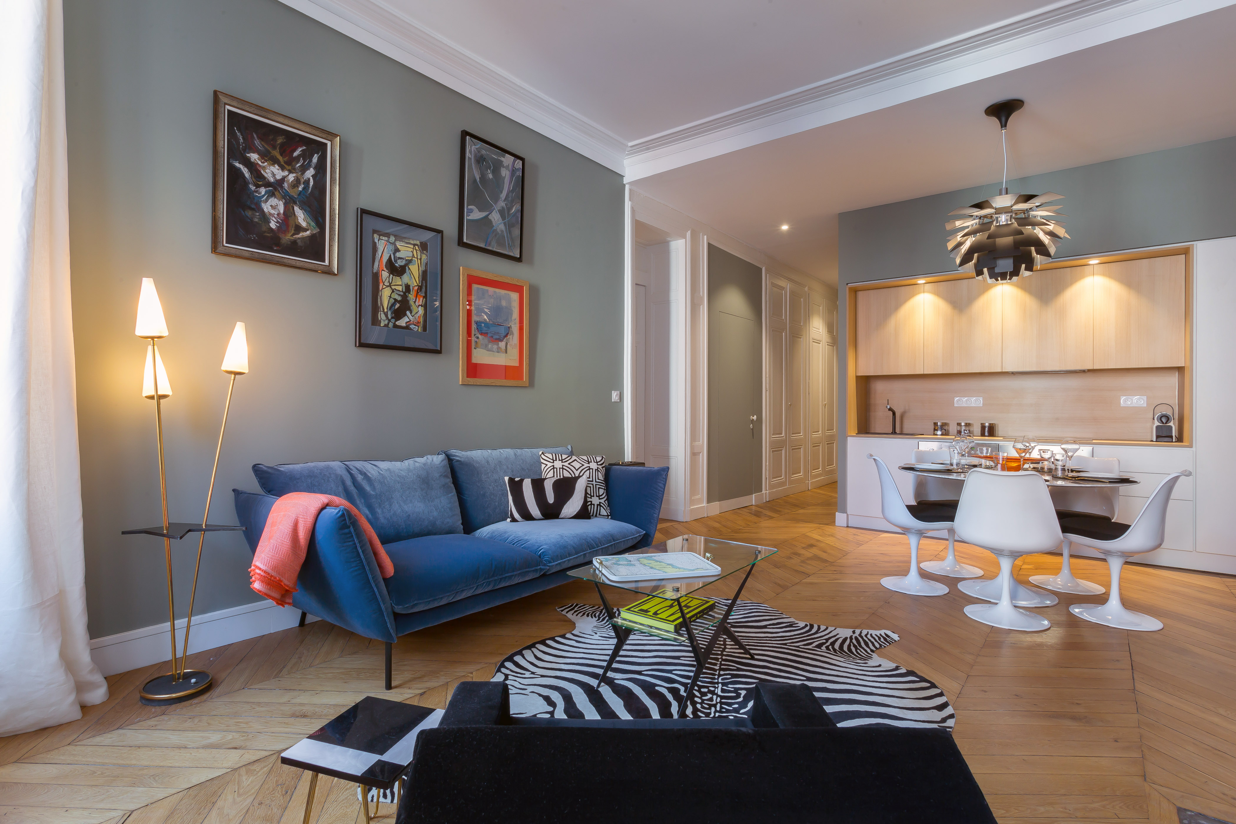 Salon de l’appartement Confort, avec canapé bleu et cuisine ouverte.