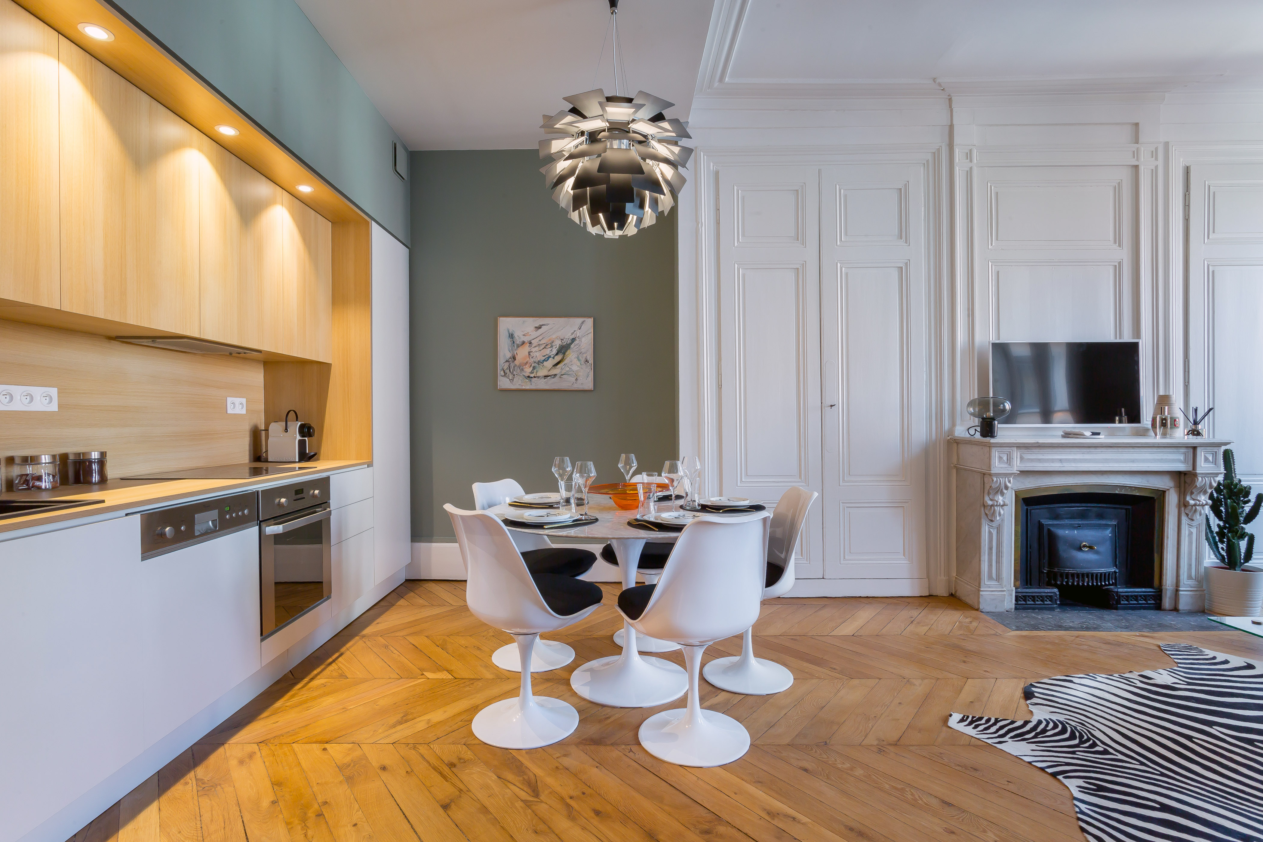 Cuisine et espace repas de l’appartement Confort, avec table ronde et cheminée.