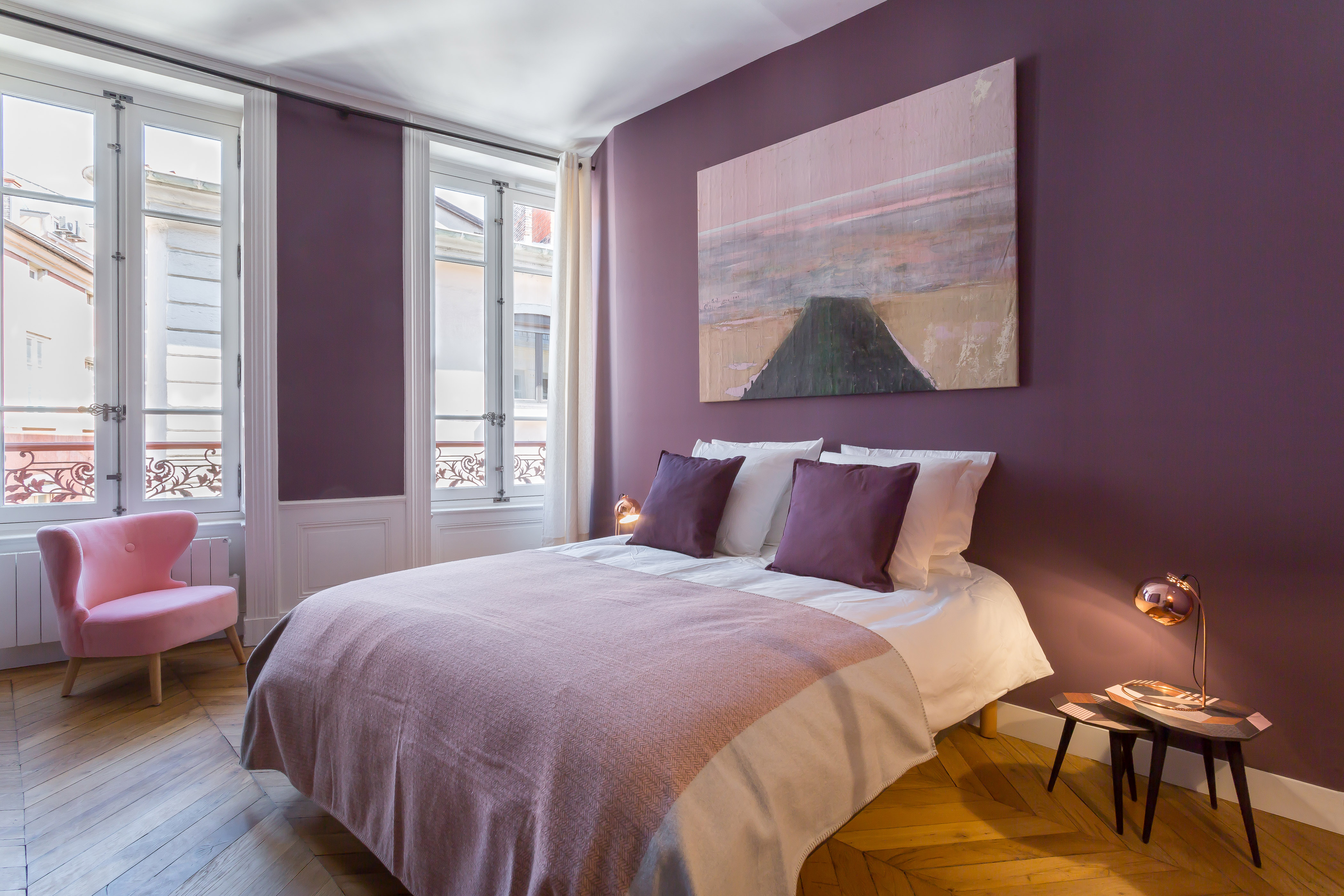 Chambre de l’appartement Confort, avec mur mauve et grandes fenêtres.