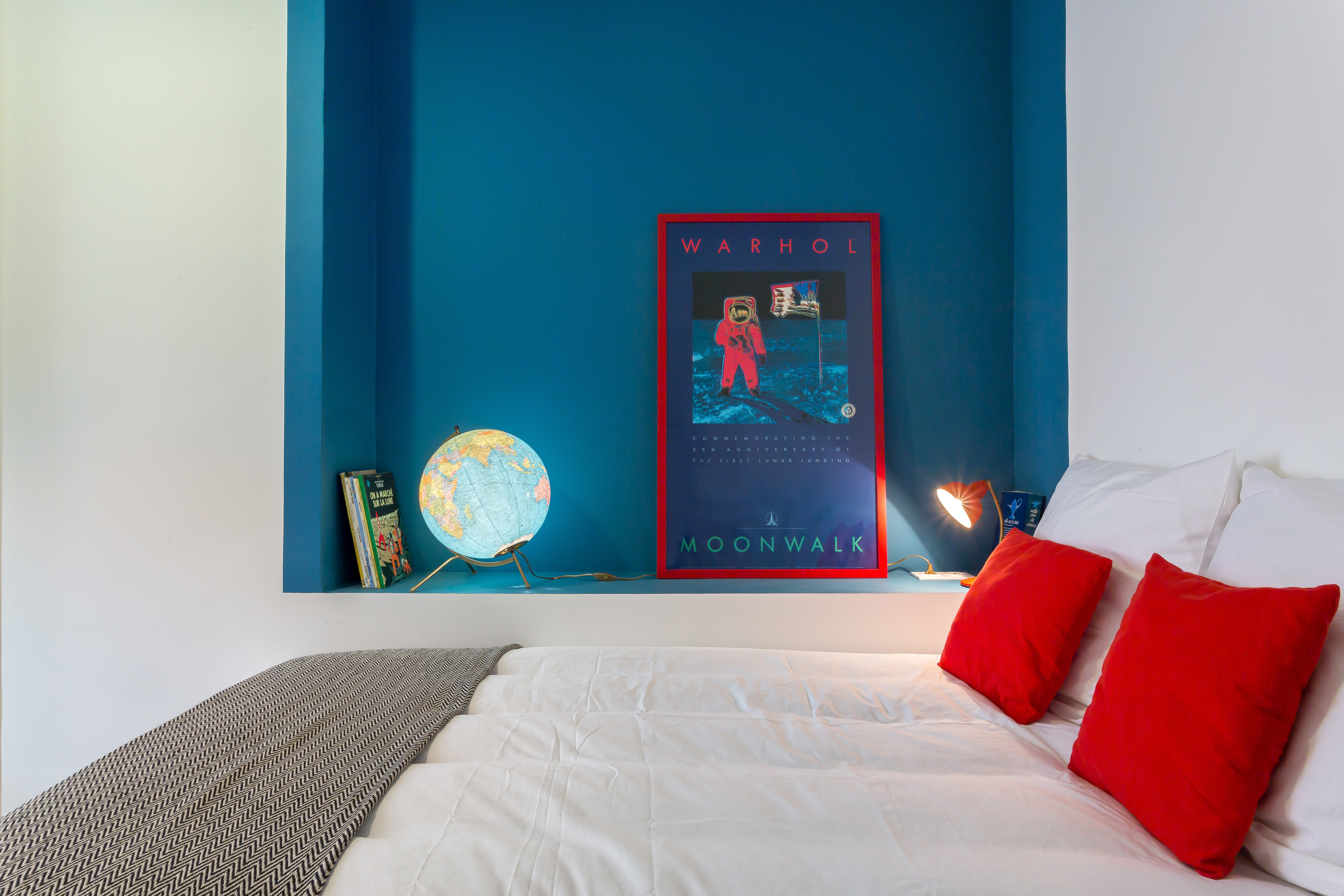 Chambre de l’appartement Confort, avec alcôve bleue et coussins rouges.