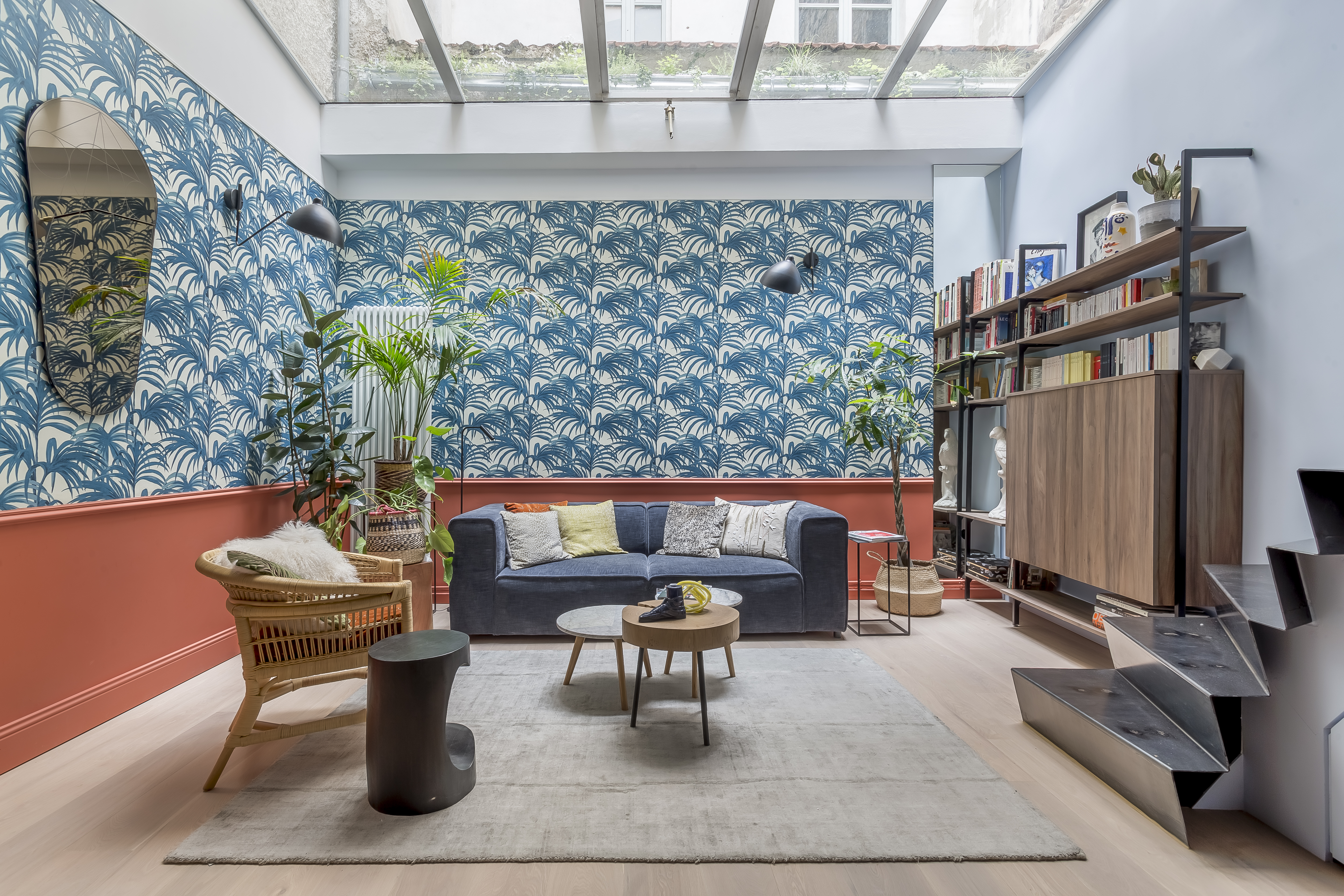 Salon de l’appartement Jungle Art à Lyon, avec verrière, décor végétal et canapé bleu.