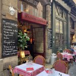 Restaurant français traditionnel à l'extérieur, avec nappes à carreaux rouges, chaises en bois et menus à la craie. Appréciée des propriétaires exigeants, l'entrée du Bouchon Lyonnais donne sur une rue à l'atmosphère chaleureuse et accueillante. | 2BeApart Lyon